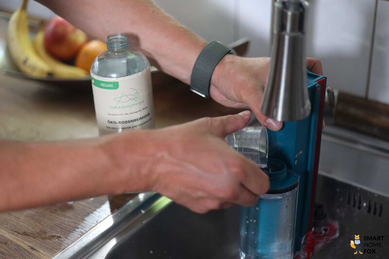 Grashüpfer Bodenreiniger wird in den Wassertank gegeben.